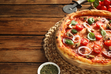 Delicious pizza with salami, vegetables, mushrooms and basil on wooden table, closeup. Space for text