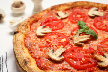 Delicious pizza with tomatoes, mushrooms and basil on table, closeup