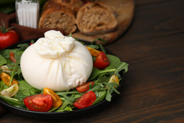 Delicious burrata salad on wooden table, closeup. Space for text