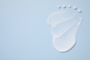 Face cream on light blue background, top view. Space for text