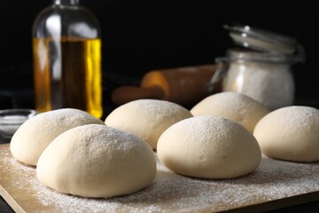 Raw dough balls with flour on table
