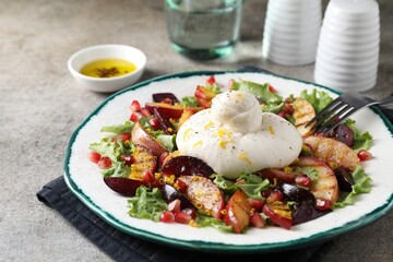 Plate with fresh burrata salad on grey textured table, closeup