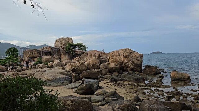 4k pan tilt a Hon Chong cape rock garden by the sea. Tourists travel walking on huge coastal boulders in Hon Chong rock garden in Nha Trang city, Vietnam.