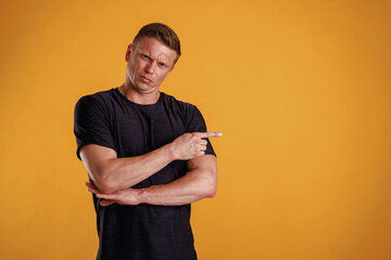 Showing to the side, pointing. Man is against background in the studio