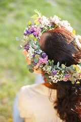 Naklejka premium woman brunette wearing flowers floral wreath - bridal florist accessories from above closeup with sunset light, boho style fashion
