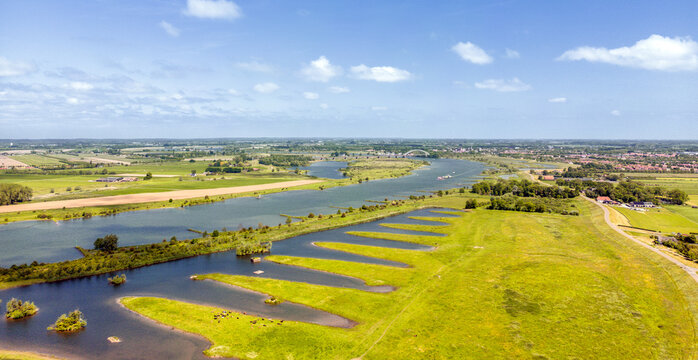 Aerial photo of the flood plains along the Lek River with a train bridge and the city of Culemborg on the horizon.