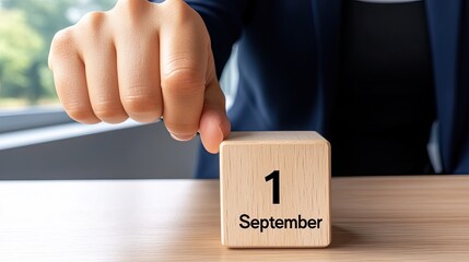 Hand Pointing at a Calendar Block Marking September 1st in a Modern Office Setting
