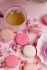 macaroon cookies with flower petals on the table and a cup of tea