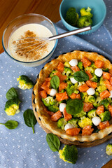 The process of making homemade French quiche pie with broccoli, spinach and salmon on blue plate