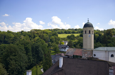 A clock tower with a dome and a cross on the roof. Church near the castle. In the background nature and blue sky with clouds.