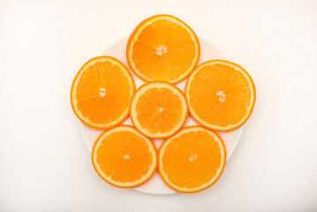 Flat slices of orange on a white plate. Chopped fruits.