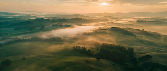 Aerial view of breathtaking sunrise over misty landscape with rolling hills and verdant fields