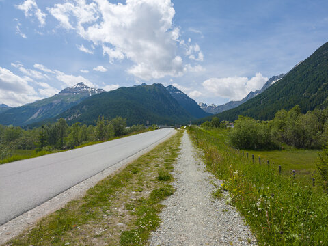 Stra&szlig;e und Gehweg mit Blick auf auf den Berg Piz Ot in der Schweiz im Kanton Graub&uuml;nden