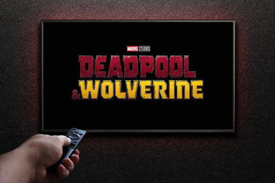 Wolverine and Deadpool trailer or movie on TV screen. Man turns on TV with remote control. Astana, Kazakhstan - July 31, 2024.