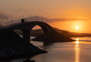 Midnight sun over a bridge in the Lofoten islands, Northern Norway with amazing orange light behind bridges