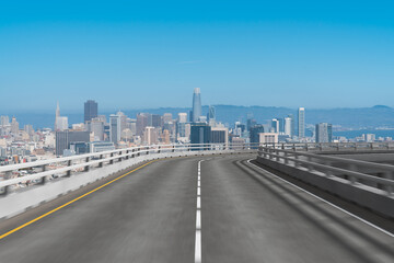 Elevated highway leading to cityscape under blue sky.