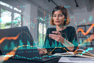 Businesswoman analyzing stock market data on smartphone at office desk.