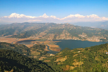 Obraz premium View onto Phewa Lake in front of a mountain range with Mount Machapuchare in the middle, on the way up to the World Peace Pagoda close to Pokhara, Nepal