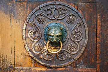 Old brass door knocker on wooden door.