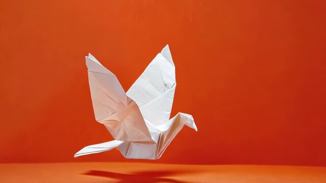 Origami bird on orange background, demonstrating the art of paper folding and creativity.