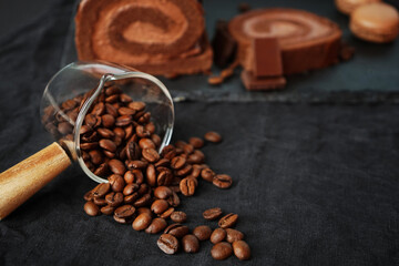 Coffee beans on a background of chocolate roll and chocolate on a dark background