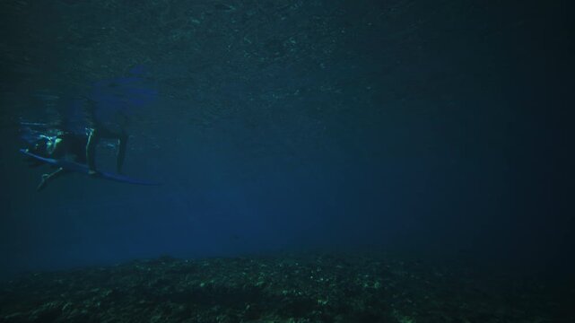 Pan across to person pushing board underwater duck diving as powerful wave energy passes over