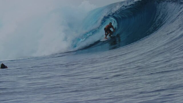 Surfer crouches down as they get barreled in heavy wave of Cloudbreak Fiji