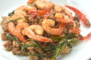 spicy stir fried chop pork with chili and basil leaf topping shrimp on plate  