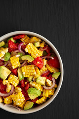 Healthy Fresh Corn Salad in a Bowl on a black background, top view. Flat lay, overhead, from above. Copy space.
