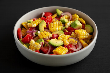 Healthy Fresh Corn Salad in a Bowl on a black background, side view. Close-up.