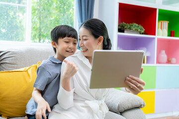 Fototapeta premium A mother and her 10-year-old son are enjoying a digital tablet together in the living room