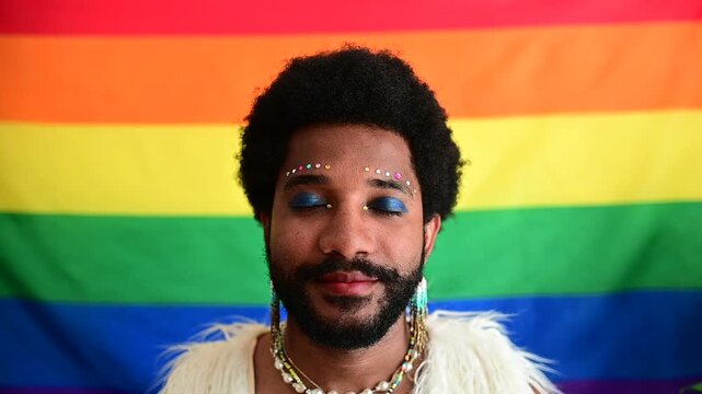 Young gay black man with festive make-up opens his eyes and smiling