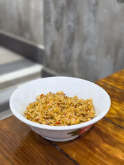 Spicy fried rices in white bowl on wooden table.