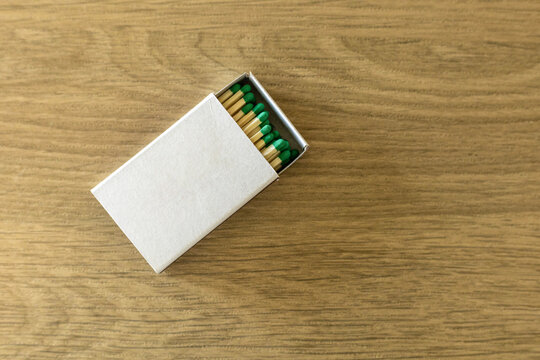 White cardboard box with green matches matchbox on wooden surface. copy space mock up concept