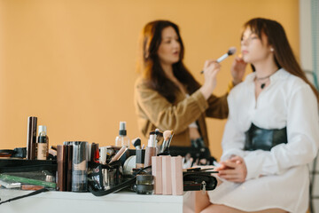 Selective Focus: Makeup Artist Prepares Model for a Photo Shoot in Studio