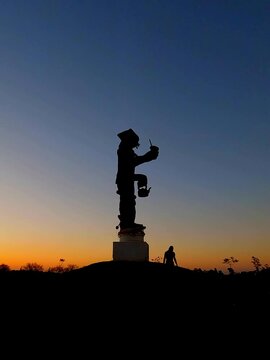 mulher caminhando ao lado de est&aacute;tua que homenageia a figura do ga&uacute;cho em Alegrete, Rio Grande do Sul 