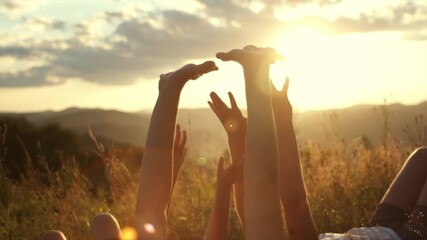 Dreaming children lying on grass with arms up on background mountains. Preteen girls raising hands up during amazing sunset. Children enjoying rest at nature. Freedom emotion and flying thoughts