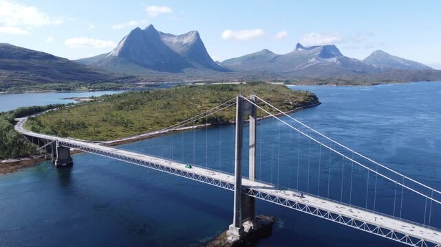 Aerial drone view of bridge in Northen Norway with cars driving on top and sharp mountains in the background
