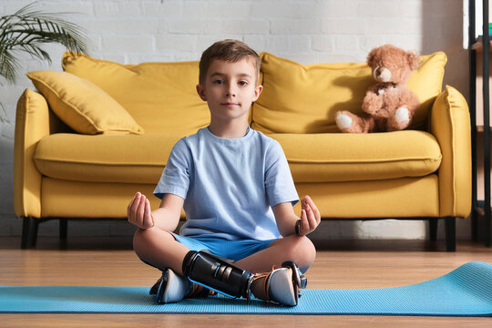 Kind mit Beinprothese macht zu Hause Yoga