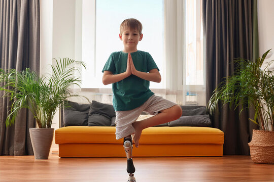 Kind mit Beinprothese macht zu Hause Yoga