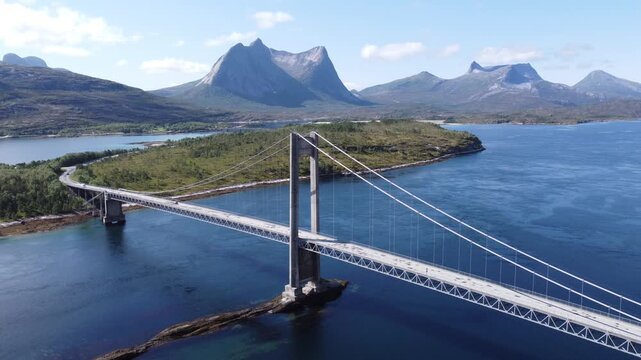 Aerial drone view of bridge in Northen Norway with cars driving on top and sharp mountains in the background