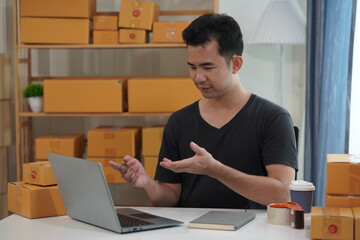 Asian male business owner selling products on websites and online platforms Selling products and packing products into parcel boxes to customers through delivery services, SME business