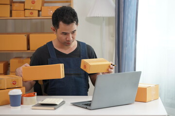 Asian male business owner selling products on websites and online platforms Selling products and packing products into parcel boxes to customers through delivery services, SME business