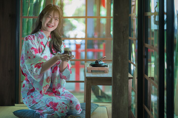 A pretty Asian girl in yukata wearing a traditional Japanese kimono or yukata happy and relaxed...