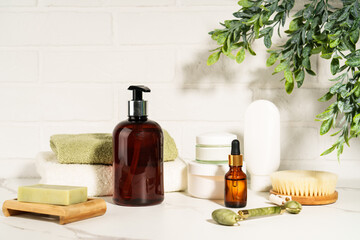 Natural cosmetic products in the bathroom on white background. Soap, serum bottle, jade roller.
