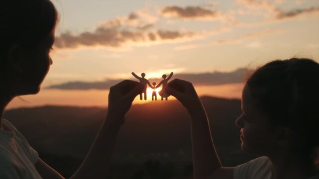 Silhouette two cute little sisters holding paper family cutout on background amazing warm sunset and mountains, foster care, world mental health day, Autism support, budgeting cost of living concept