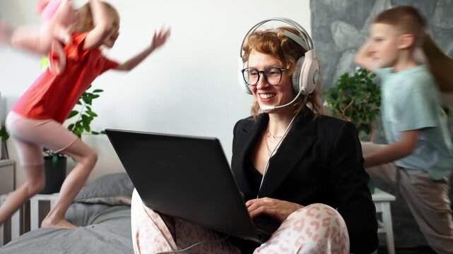 Remote work at home: A girl in a jacket and pajamas, a call worker contacts a client via video conference. Children run around, make loud noises and get in the way.