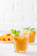 Fototapeta premium Peach and nectarine ice and mint lemonade on a light background. Homemade cold summer drink. Vertical orientation.
