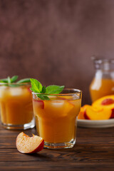 Refreshing peach ice and mint cocktail on a wooden table. Homemade cold summer drink. Vertical orientation.