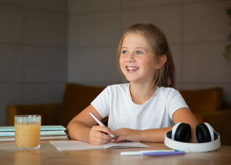 Cute little girl doing her homework at home, sitting at a table.